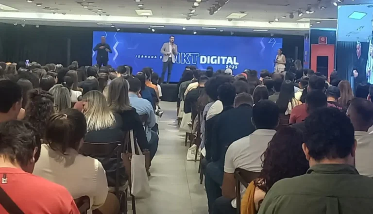 Palestrantes renomados no palco da Jornada de Marketing Digital em Cuiabá, com plateia engajada e telão com o tema do evento e logo do Sebrae/MT.